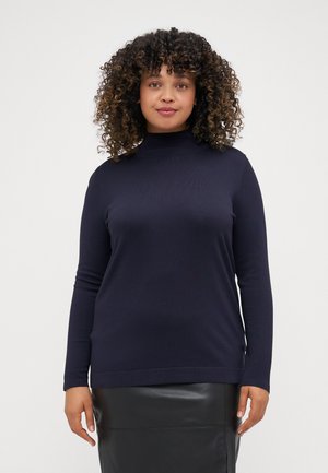 Navy turtleneck sweater in soft, knitted fabric with long sleeves and a fitted shape, paired with a black, glossy leather skirt.