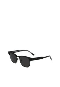 Occhiali da sole neri con finitura opaca, montatura rettangolare, lenti scure e dettagli metallici sulle tempie. Marchio Lacoste sul lato.