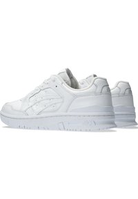 Scarpe sportive bianche con tomaia in pelle liscia, design con lacci, linguetta e colletto imbottiti, e suola in gomma testurizzata, caratterizzate da un logo sul tallone.