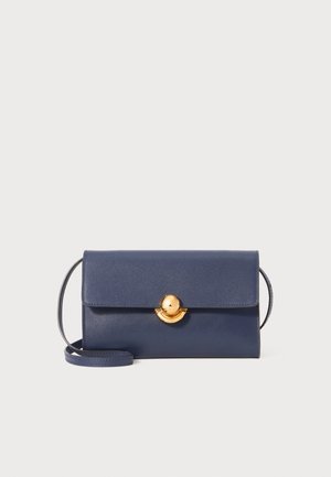 Navy leather handbag with a structured design, featuring a gold circular clasp and a detachable shoulder strap. Smooth texture and clean lines.