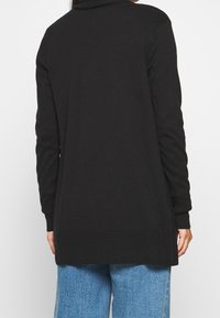 Schwarzer langärmliger Cardigan mit hohem Kragen, geripptem Saum und seitlichen Schlitzen. Hergestellt aus weichem Material mit glatter Textur.