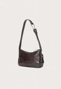 Dark brown leather shoulder bag with a smooth texture, curved shape, adjustable strap, and silver hardware. Zipper closure at the top.