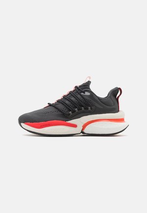 Scarpa sportiva nera con accenti rossi, tomaia in rete, sei lacci e una suola bianca spessa dotata di tecnologia di ammortizzazione.