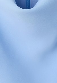 Nærbillede af lyseblåt stof med rund halsudskæring og en synlig blå lynlås bagpå.