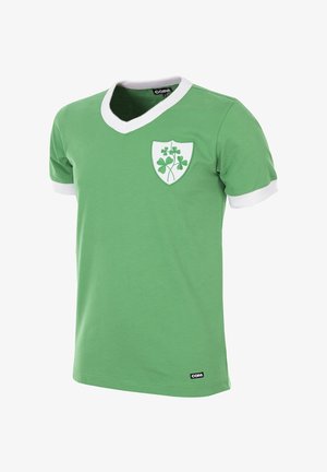 Groene T-shirt met een V-hals en witte kraag. Heeft een witte schild op de borst met een klaverafbeelding. Gemaakt van zachte stof.