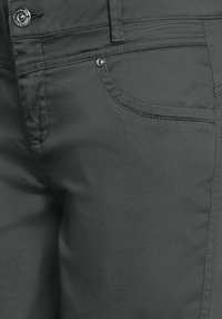 Jeans in denim grigio elasticizzato con una texture liscia, dotati di tasche standard e bottoni in metallo sulla vita.
