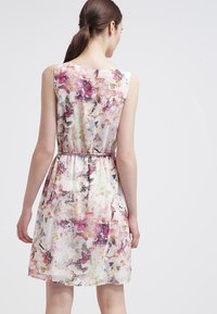 Ärmlös klänning i lätt tyg med ett färgglatt blommönster och fjärilar. Elastisk midja och flödande A-linjeform.