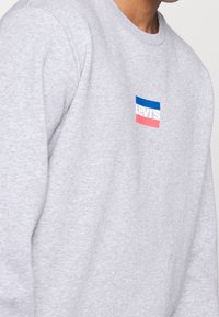 Felpa grigia in cotone misto, con un piccolo logo "Levi's" multicolore sul petto. Design classico con collo a girocollo.