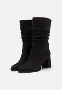 Bottes souples noires en daim doux, dotées d'un talon bloc et d'une texture froncée à la cheville, avec un design à bout rond.