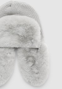 Szara dzianinowa czapka z nausznikami z futerka syntetycznego. Materiał jest miękki, z teksturowanym wzorem dzianiny na górze oraz puszystymi, gładkimi nausznikami.