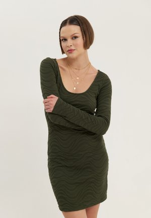 Olive green long-sleeve dress with a wavy texture, fitted silhouette, scoop neckline, and a mini length, complemented by layered gold necklaces.