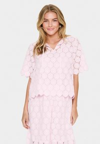 Light pink lace top with short sleeves, floral pattern, scalloped hem, and hood. Paired with matching lace skirt for a coordinated look.