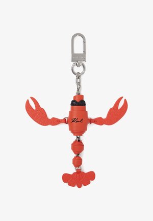 Punase homaari kujuline võtmehoidja metallist kinnituse ja kettiga, millel on kehale trükitud signatuur "Karl" ning tekstureeritud küünte detailid.