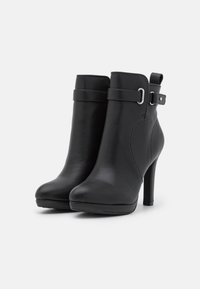 Black leather ankle boots with a pointed toe, a high stiletto heel, and an adjustable strap with a silver buckle detail. Smooth texture.