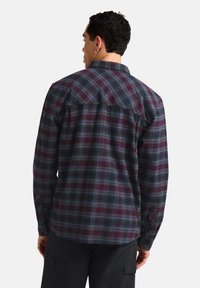 Chemise à carreaux pour homme dans des tons de bordeaux foncé et de bleu ; présente des manches longues, un col et des poignets à boutons ; fabriquée en tissu doux et texturé.