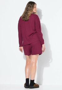 Conjunto de loungewear burdeos que incluye una camiseta de manga larga de corte holgado y pantalones cortos a juego, con un patrón de punto waffle texturizado.
