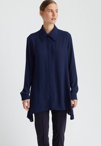 Marineblaues Langarmhemd aus leichter Stoffqualität, mit klassischem Kragen, knöpfbaren Manschetten und asymmetrischem Saum.