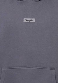 Grauer Hoodie mit einer Fronttasche, weichem Material und einem rechteckigen Etikett mit dem Markennamen "Dropsize" in schwarzer Schrift.