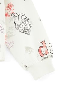 Felpa bianca con illustrazioni grafiche che includono un cuore, rose e disegni astratti in rosso e grigio. Polsini a costine e texture morbida.