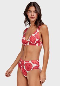 Bikini s uzorkom crvenih cvjetova koji sadrži bralette top s V-izrezom i širokim trakama te gaćice viskog struka. Izrađen od glatkog, rastezljivog materijala.