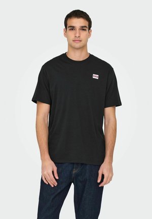 Black cotton t-shirt with short sleeves, round neck, and a small, red-and-white logo patch on the upper left chest. Casual fit.