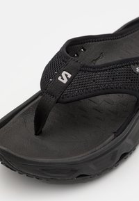 Černé žabky s texturovanou gumovou podrážkou, síťovanými popruhy a logem. Nabízí design thong a sportovní vzhled.