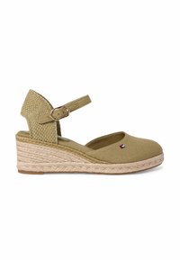Espadrille compensée beige avec bride à la cheville, talon tissé, et petit logo drapeau rouge, blanc et bleu sur le côté.