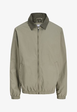 Lysebeige jakke med glidelås, mørkegrønn krage, elastiske mansjetter og kant, og skrå lommer på begge sider.