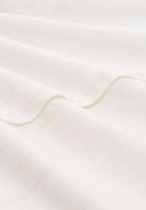 Weißer Stoff mit einem subtilen strukturierten Streifenmuster und glänzenden Akzenten. Verfügt über kleine Knöpfe entlang einer Kante zum Verschließen.