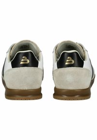 Bílé a šedé tenisky s černými akcenty, semišové a kožené materiály, zlaté logo, plochá gumová podrážka, kontrastní textury a prošívané detaily.