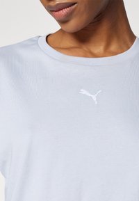 Light blue cotton t-shirt with a round neckline, featuring a small white embroidered logo on the chest and a smooth, soft texture.