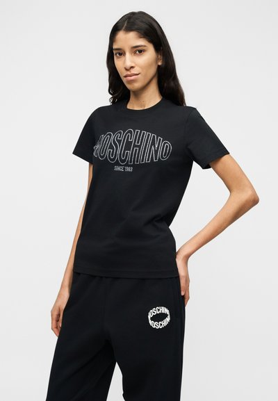 Μαύρο βαμβακερό T-shirt με κοντά μανίκια και λογότυπο από λευκούς στρας. Συνδυάζεται με μαύρη φόρμα με λευκό λογότυπο.