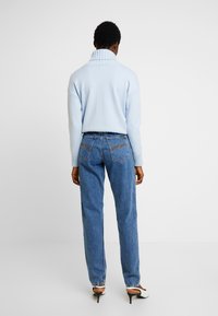 Ljusblå, ribbad polotröja matchad med högmidjade, avslappnade blå jeans med kontrasterande sömmar och bakfickor.