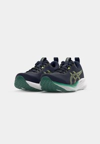 Hardloopschoenen met een marineblauwe bovenkant, heldergroene accenten, witte tussenzool en een textuur van de groene buitenzool. Inclusief een trekband voor gemakkelijke aan- en uittrekken.