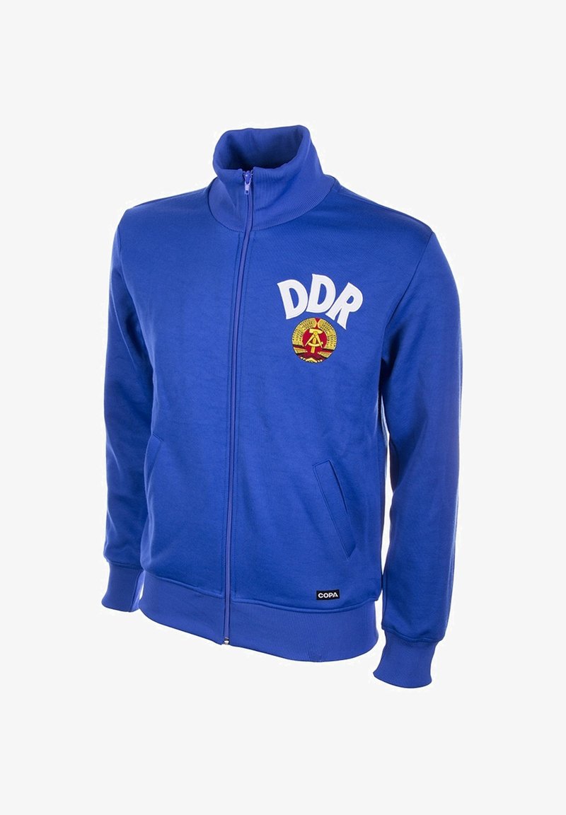 Blauwe zip-up sweatshirt met hoge kraag. Voorzien van "DDR" in witte tekst en een ronde embleem. Het materiaal is zacht met ribgebreide boorden en onderkant.