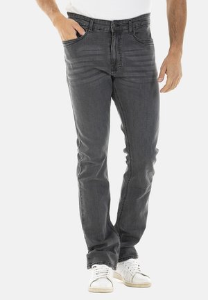 Jeans en denim gris foncé avec une coupe slim, design à cinq poches, légère décoloration et fermeture éclair, associés à des baskets blanches.