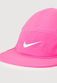Pink Nike cap with a curved visor, made of lightweight fabric. Features a prominent white Nike swoosh logo on the front.