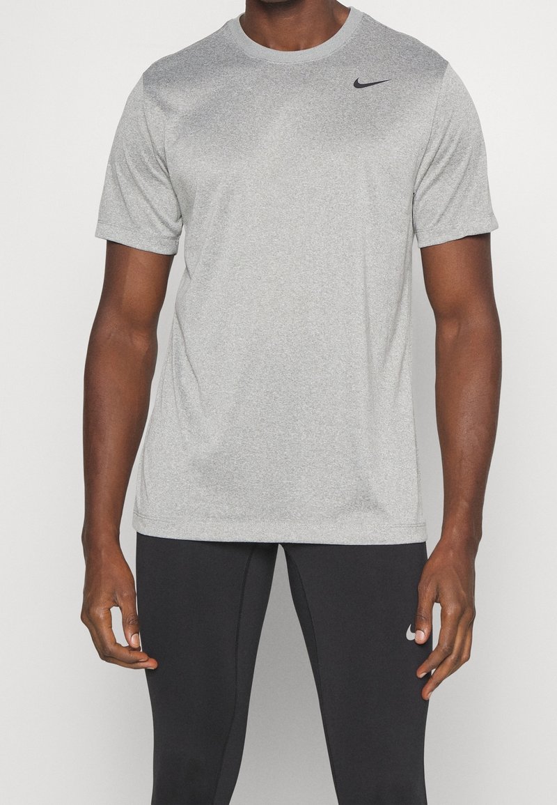 Camiseta atlética de manga corta en gris, hecha de un tejido transpirable, con cuello redondo y un pequeño logo negro de Nike en la parte superior izquierda.