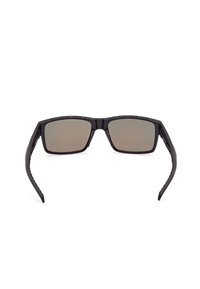 Lunettes de sport rectangulaires noires avec des verres teintés foncés et des branches épaisses incurvées et légèrement évasées.