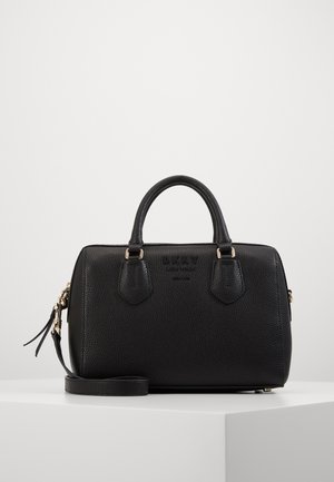 Schwarze, strukturiert geprägte Leder-DKNY-Handtasche mit zwei Griffen und abnehmbarem Riemen, präsentiert auf einem weißen Podest vor einfarbigem Hintergrund.