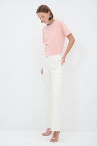 Light pink short-sleeve t-shirt with a beaded neckline, paired with high-waisted white straight-leg jeans and silver embellished sandals.