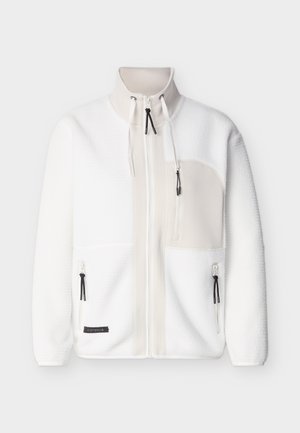 Λευκό μπουφάν από φλις με ψηλό γιακά, πλήρης φερμουάρ μπροστά, τσεπάκι στο στήθος με φερμουάρ, δύο χαμηλές τσέπες με φερμουάρ και μαύρα τερματικά φερμουάρ.