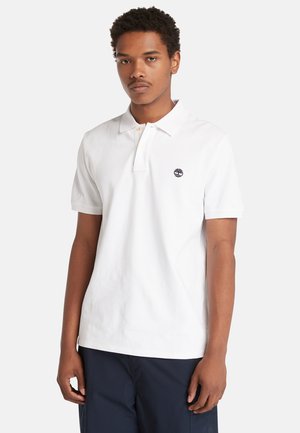 Polo in cotone bianco con colletto a tre bottoni e maniche corte. Presenta un piccolo logo nero sul lato sinistro del petto, texture liscia.