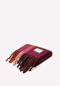 Gebreide sjaal met een verloop van bordeauxrood, roze en oranje tinten en zachte franjes aan de randen. Label met de tekst "ARCTIC FOX" bevestigd.