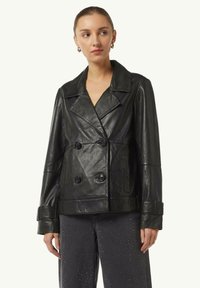 Schwarze Leder-Doppelkörperjacke mit Reverskragen, großen Knöpfen und Seitentaschen; hat eine lockere Passform und maßgeschneiderte Manschetten.