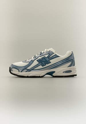 Hvid og blå atletiksneaker med mesh overdel, snørelukning, polstret sål og mærket logo på siden, vist i profil.