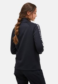Giacca atletica nera con colletto alto, texture liscia e logo stampato sulle maniche. Presenta un design aderente e una costruzione pratica.