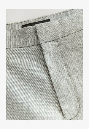 Šedá denimová látka s jemným rybim vzorom, vybavená štruktúrovaným pásom a detailom horného prešívania, vopred naklonenou klopou vrecka.