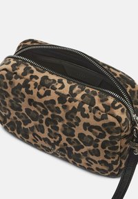 Torba na ramię w panterkę, wykonana z miękkiego zamszu, z czarnym wnętrzem, metalowym zamkiem błyskawicznym oraz regulowanym paskiem do noszenia na różne sposoby.