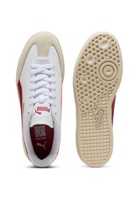 Weiße und rote Puma-Sneaker mit Wildlederakzenten, flachen Schnürsenkeln, strukturiertem creamfarbenen Außensohle und Logodetails an der Seite und auf der Zunge.